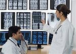 Ärztin untersuchen Röntgen-Bericht und ihre Kollegin am Telefon sprechen