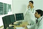 Médecin de sexe masculin examine le rapport des rayons x et son collègue parler sur un téléphone