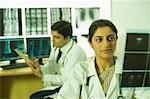 Female doctor examining X-Ray report and her colleague writing prescription