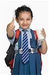 Schoolgirl holding a glass of milk and showing thumbs up sign
