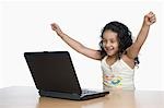 Girl cheering in front of a laptop