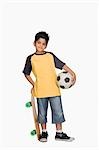 Garçon tenant une planche à roulettes et un ballon de soccer