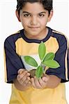 Portrait of a boy holding a plant