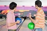 Two young men holding bowling balls in a bowling alley