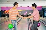Zwei junge Männer, Hände schütteln, in eine Bowlingbahn