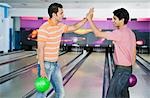Deux jeunes hommes High-Five dans une ruelle de bowling