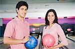Young couple holding bowling balls in a bowling alley