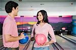 Young couple holding bowling balls in a bowling alley