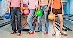 Two young couples holding bowling balls in a bowling alley