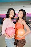 Deux jeunes femmes tenant des boules dans un bowling