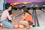 Deux jeunes femmes avec des boules de bowling dans une ruelle de bowling