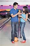 Jeune couple avec une boule de bowling et un trophée dans un bowling