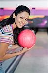 Junge Frau hält eine Bowling-Kugel in eine Bowlingbahn