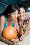Deux jeunes femmes, en regardant un téléphone mobile dans un bowling
