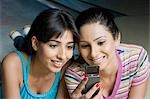 Two young women looking at a mobile phone in a bowling alley