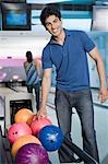 Jeune homme prendre une boule de bowling et une jeune femme bowling dans une ruelle de bowling