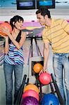 Young couple picking bowling balls and smiling in a bowling alley