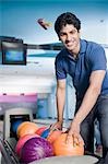 Young man picking a bowling ball in a bowling alley