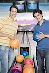 Zwei junge Männer in eine Bowlingbahn Bowling-Kugeln halten