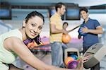 Young woman operating the control panel and her friends in the background in a bowling alley