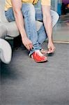 Low section view of a young man tying his shoelace in a bowling alley