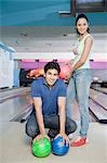 Portrait d'un jeune couple avec une boule de bowling dans une ruelle de bowling