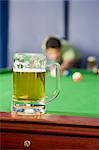Junger Mann spielen, Pool und ein Bierglas gehalten auf dem Billardtisch