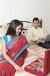 Woman choosing bangles while her husband working on a laptop