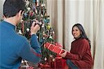 Man filming his wife with Christmas presents