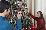 Man filming his wife decorating Christmas tree