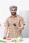 Man chopping vegetables and using a mobile phone