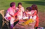 Family celebrating Holi with traditional Indian cuisines