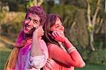 Couple in Holi colors talking on mobile phones