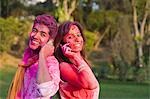 Couple in Holi colors talking on mobile phones