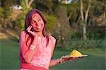 Woman holding a plate of gulal and talking on a mobile phone