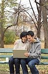 Couple Using Laptop Computer on Park Bench