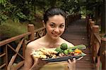 Girl holding a tray full of ingredients for Jamu, the Indonesian herbal elixir, Indonesia, Southeast Asia, Asia