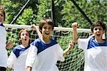 Garçons sur le terrain de soccer, poings soulevées dans la victoire