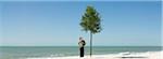 Boy admiring tree growing on beach