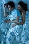 Couple ensemble dans le lit, femme embrassant l'homme, l'observant dormir