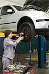 Mechanic changing tires of car elevated on hydraulic lift