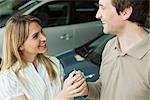 Couple in car dealership showroom with key to new car