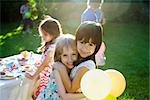 Young friends embracing at outdoor party, portrait