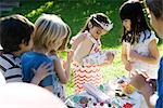 Girl opening gift at birthday party as friends watch