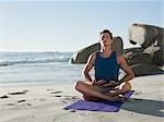 Young man doing yoga on beach