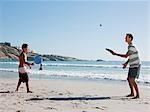 Father and son on playing paddleball on beach
