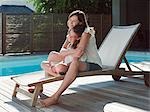 Fille et mère sur une chaise longue au bord de piscine