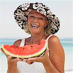 senior woman on beach holding water melon