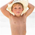 Boy (6-8) on beach wearing straw hat