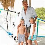 Grandfather and grandchildren (6-8) on beach by windsurfer